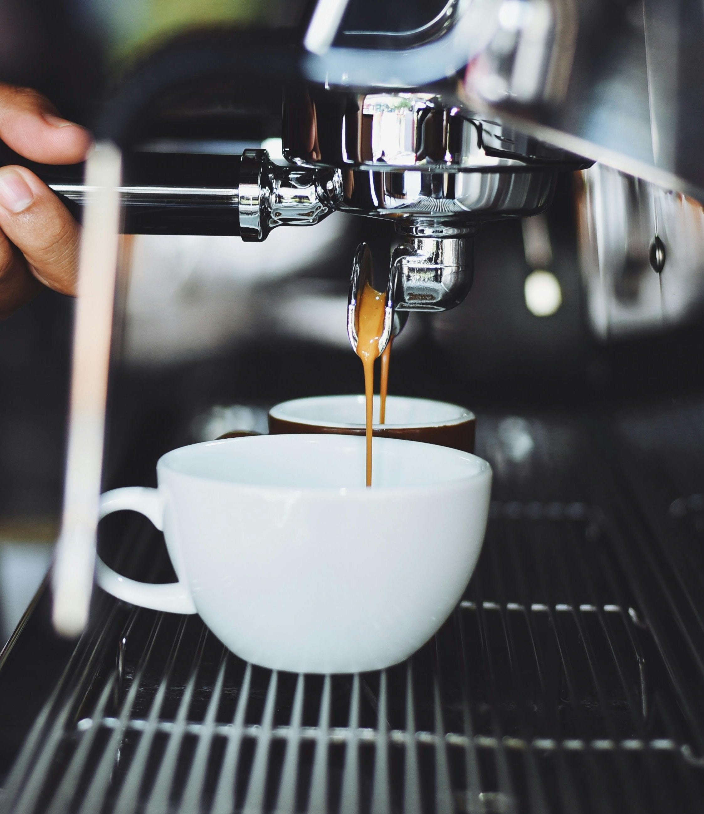 Pulling a double shot of espresso using a double sprouted portafilter into white cups