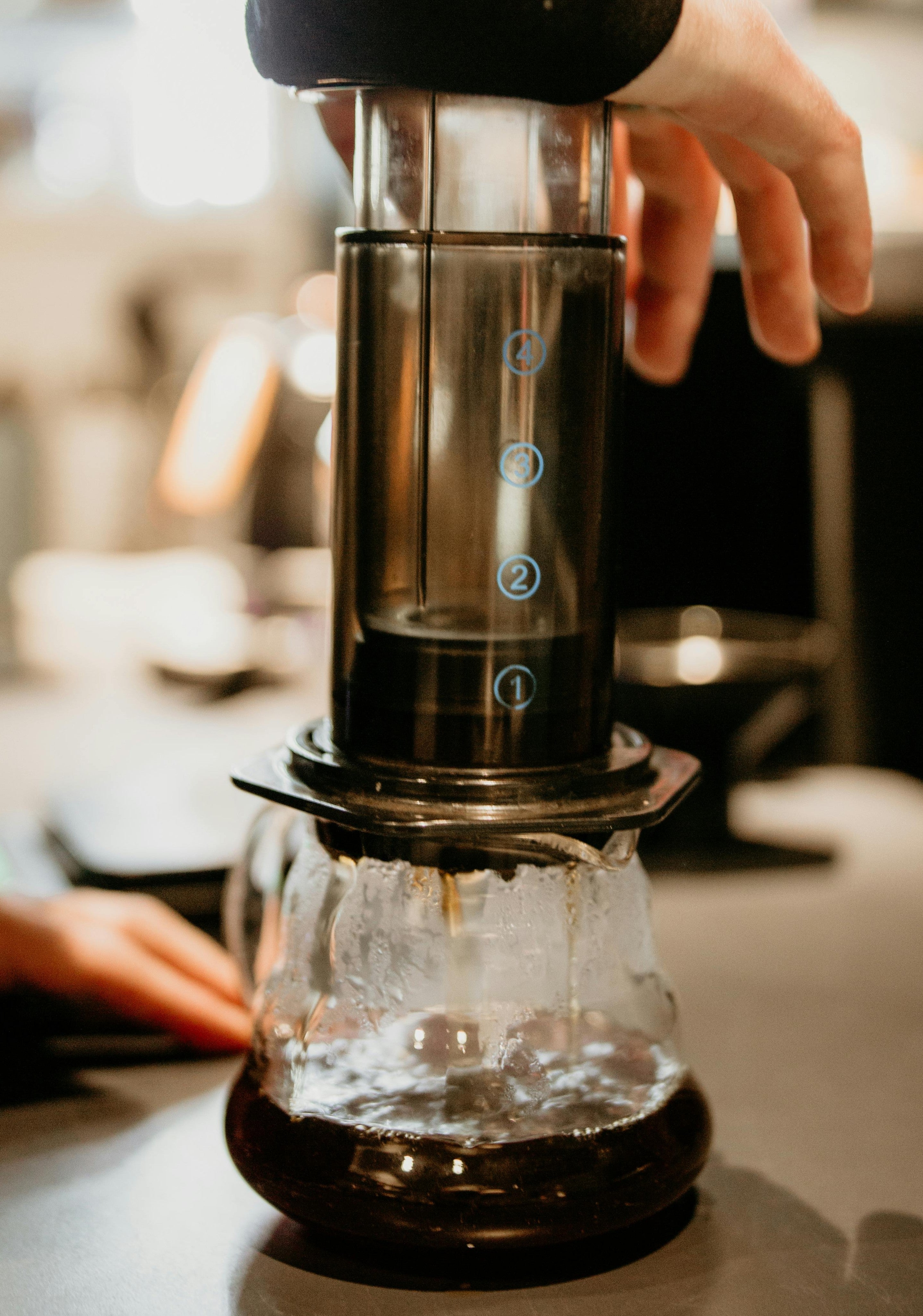 Coffee being brewed and pressed down through a black Aeropress into a transparent flask