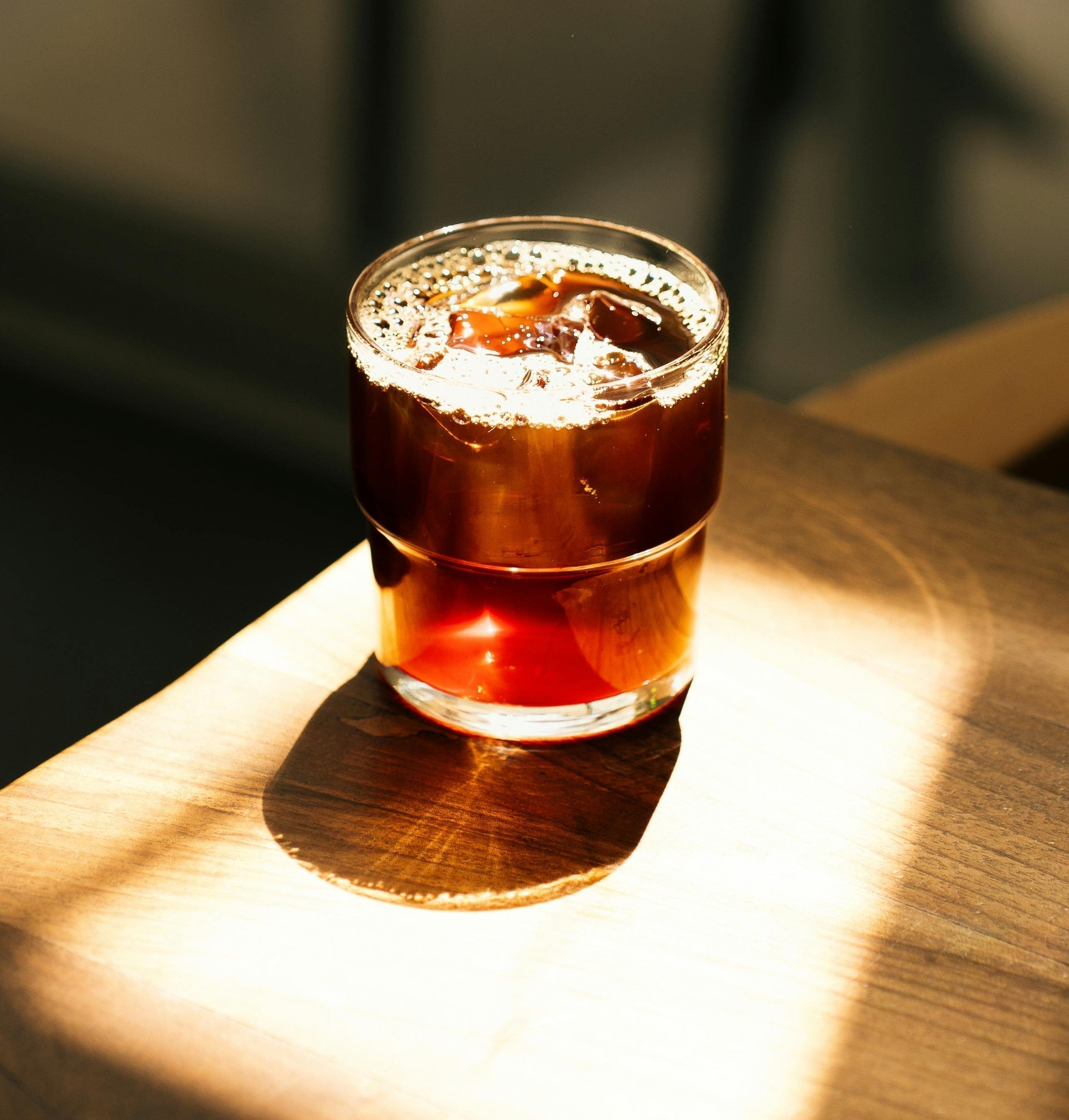A cup of cold brew coffee under the sunlight on a wooden table