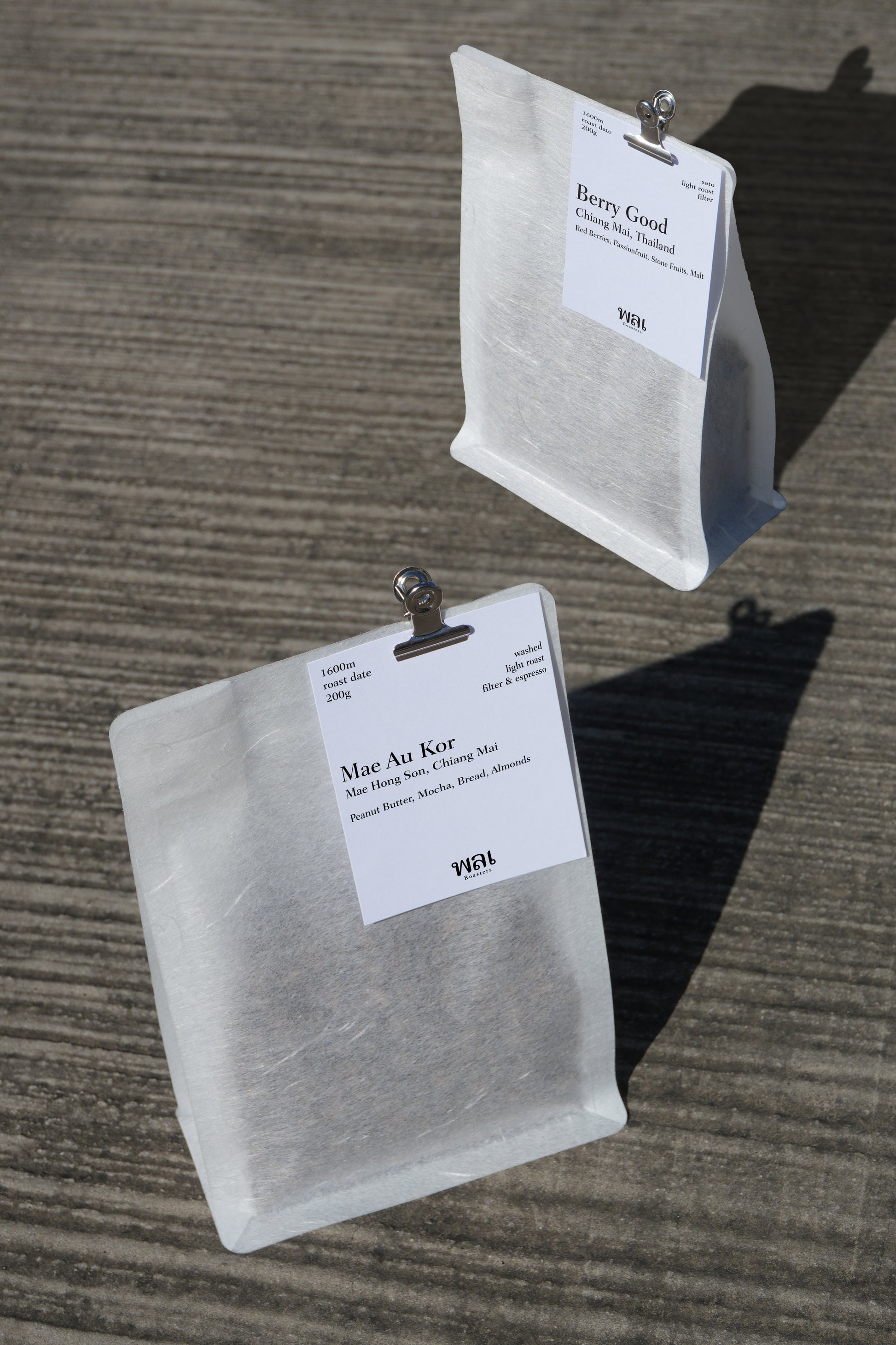 Two white tea bags with labels on a textured surface
