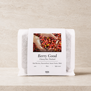 a bag of thai coffee beans in a translucent bag with a white paper sleeve with the words berry good on it on a stone background and ledge made for filtered coffee